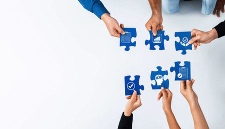 Diverse hands grasp puzzle pieces symbolizing teamwork and collaboration, highlighting strategic growth and analysis for successful business execution.の写真素材