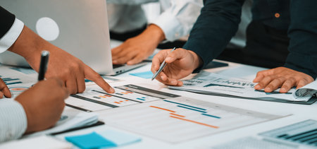 A diverse team engages in a productive discussion while analyzing data reports and charts on a...