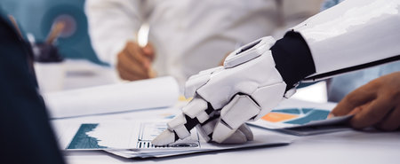 A robotic hand is interacting with documents during a business meeting, symbolizing the fusion of...