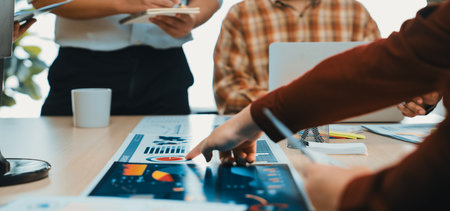 A dynamic office scene showcasing professionals engaged in a collaborative meeting, analyzing data charts and discussing strategies to enhance productivity and insights.の写真素材