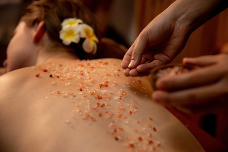 Woman customer having exfoliation treatment in luxury spa salon with warmth candle light ambient. Salt scrub beauty treatment in Health spa body scrub. Quiescentの写真素材