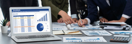 Panorama shot analyst team utilizing BI Fintech to analyze financial report with laptop. Businesspeople analyzing BI data dashboard displayed on laptop screen for business insight. Prodigyの写真素材