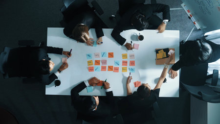Top down aerial view of skilled diverse business group choosing marketing strategy while businessman standing and presenting project by using mind map at meeting room. Teamwork concept. Directorate.の写真素材