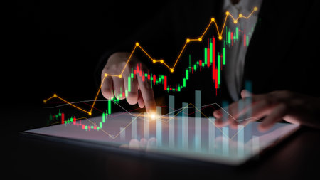 A business professional engages in financial analysis using a digital tablet to explore stock market trends, detailed graphs, and dynamic data in a sleek environment.の写真素材