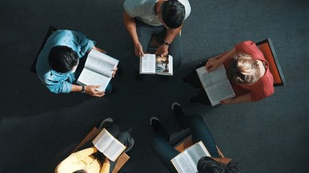 Top down view of prayer reading at bible book and sitting in circle with bible book on laps. Aerial view of diverse people looking at book while studying with faith, trust and hope, calm. Symposium.の写真素材