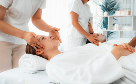 Serene modern daylight ambiance of spa salon, couple customer indulges in rejuvenating with facial skincare mask. Facial skin treatment and beauty cosmetology procedure for face. Quiescentの写真素材