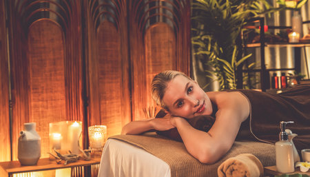 Caucasian woman customer enjoying relaxing anti-stress spa massage and pampering with beauty skin recreation leisure in warm candle lighting ambient salon spa at luxury resort or hotel. Quiescentの写真素材
