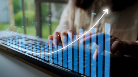A creative composition showcasing a person working on a laptop with an overlaid graph representing business growth and data analysis in a modern office setting.の写真素材