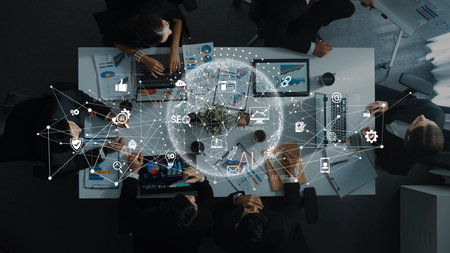 A dynamic business meeting showcasing a collaboration of professionals around a conference table, featuring technology and data analytics with global connectivity elements.の写真素材