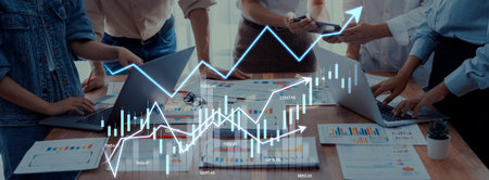 A group of professionals collaborate in a modern workspace, utilizing laptops and data visualizations to discuss business strategy and financial metrics for growth.の写真素材