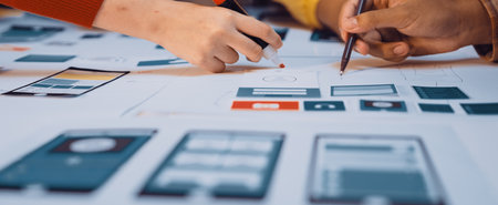 A diverse group collaborates on user interface design for a mobile application, using markers and...