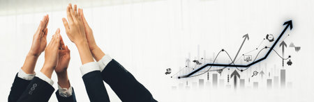 A team joyfully celebrates success with raised hands, symbolizing growth and achievement in a business environment. Graphs and charts illustrate upward progress.の写真素材