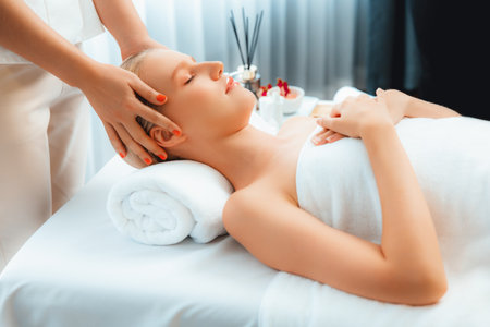 Caucasian woman enjoying relaxing anti-stress head massage and pampering facial beauty skin recreation leisure in dayspa modern light ambient at luxury resort or hotel spa salon. Quiescentの写真素材