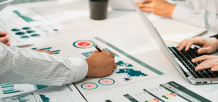 A professional team collaborates during a business meeting, analyzing financial reports and data...