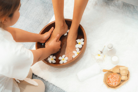 Woman indulges in blissful foot massage at luxurious spa salon while masseur give reflexology therapy in gentle day light ambiance resort or hotel foot spa. Quiescentの写真素材