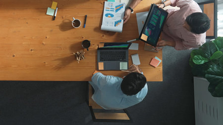 Project manager calling phone while diverse team brainstorm idea and looking at financial statistic at tablet at meeting table. Diverse business people planning marketing strategy.の写真素材