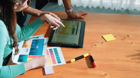 Top view of manager writing idea on sticky notes and explain idea about web design. Professional marketing team or programmer brainstorming idea while looking at tablet with color palette. Symposium.の写真素材