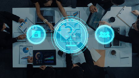 A diverse business team collaborates in a modern office, discussing cybersecurity solutions with laptops and charts. Focus on teamwork and planning in a digital environment.の写真素材