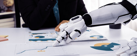 A robot arm collaborates with a businessman to review detailed data charts and graphs at an office desk, showcasing future technology in work environments.の写真素材