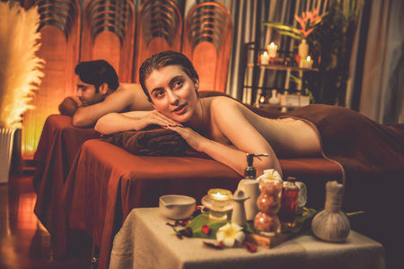 Couple customer having exfoliation treatment in luxury spa salon with warmth candle light ambient. Salt scrub beauty treatment in Health spa body scrub. Quiescentの写真素材