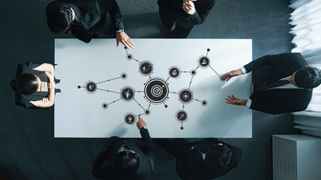 A diverse business team engages in a strategic meeting around a table with graphical data visualization, fostering collaboration and innovative solutions for future growth.の写真素材