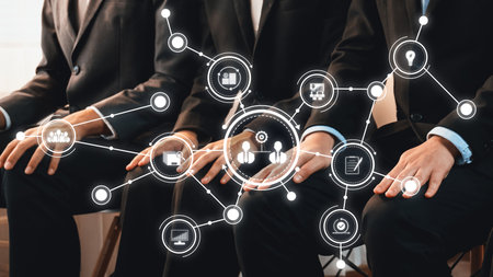 A group of business professionals is sitting together, surrounded by digital icons representing connectivity and collaboration in a modern corporate setting.の写真素材