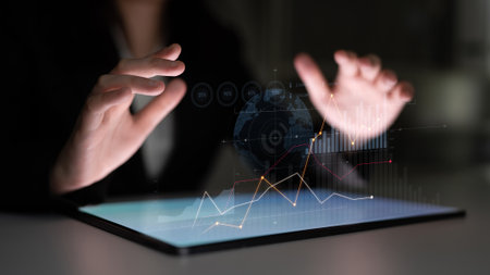 A business professional is engaged in data analysis using a tablet. Holographic graphs and charts...
