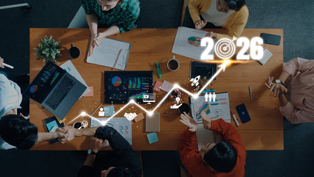 A diverse group engages in a business meeting, analyzing data and discussing growth projections for 2026. Visuals include charts and graphs in a modern office.の写真素材