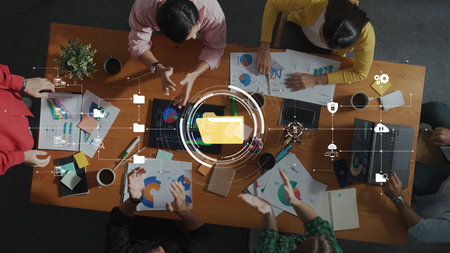 A diverse team engages in a collaborative meeting at a modern office table, surrounded by charts, graphs, and technology, fostering innovation and creativity. Rasterの写真素材