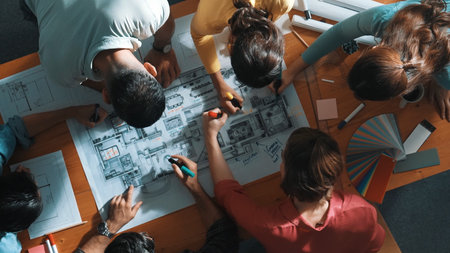 Top down view of civil engineer team writing at blueprint at meeting table with color palettes. Group of diverse people planning and taking a note while manager looking at project plans. Symposium.の写真素材