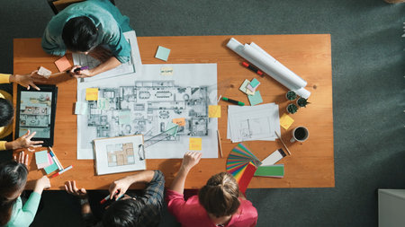 Top down aerial view of smart engineer looking at blueprint at meeting room. Skilled architect team talking and discussing while inspecting at project plan at meeting table with blueprint. Symposium.の写真素材