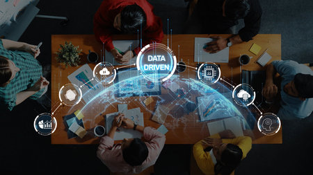 A group of diverse professionals collaborates around a table, engaging with digital data visuals and global network elements in a modern workspace environment. Rasterの写真素材