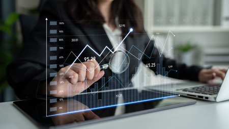 A business professional examines financial data using a magnifying glass on digital graphs and...