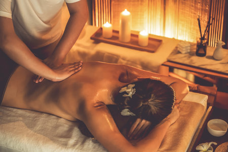 Caucasian woman customer enjoying relaxing anti-stress spa massage and pampering with beauty skin recreation leisure in warm candle lighting ambient salon spa at luxury resort or hotel. Quiescentの写真素材