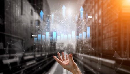 A hand reaching out towards digital financial graphs showcases growth and investment opportunities. The modern city backdrop enhances the theme of financial progress in business.の写真素材