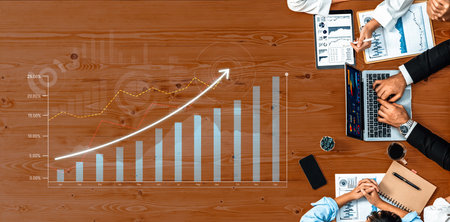 Business team engages in collaborative financial analysis using graphs and technology. A wooden...