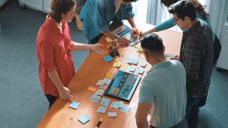 Top view of manager writing idea on sticky notes and explain idea about web design. Professional marketing team or programmer brainstorming idea while looking at tablet with color palette. Symposium.の写真素材