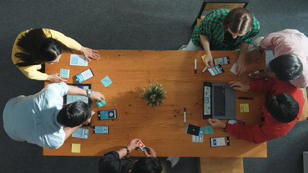 Programmer team brainstorm and plan Ux Ui design for mobile phone while present idea by using laptop at meeting. Software developer look at wireframe prototype while write at sticky note.の写真素材