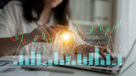 A business professional analyzes data on a laptop while interacting with a light bulb symbolizing innovative ideas and insights, representing growth opportunities and strategies.の写真素材