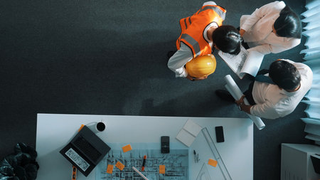 Top view of skilled architect engineer team looking at blueprint together. Aerial view of smart designer holding tablet while working together and brainstorming about building structure.の写真素材