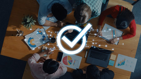 Diverse team collaborating in a modern office, analyzing charts and graphs on digital devices, focused on achieving project goals and business success. Tropeの写真素材