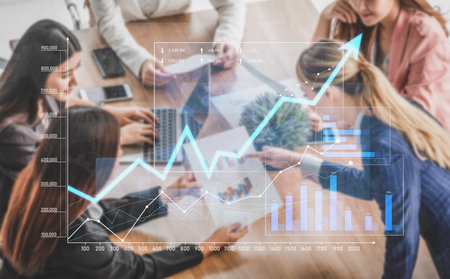 A diverse group of professionals collaborates on business strategy using financial charts and growth indicators in a modern office setting, showcasing teamwork and innovation.の写真素材