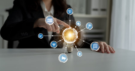 A businesswoman interacts with a light bulb symbolizing innovation and connection. The image...