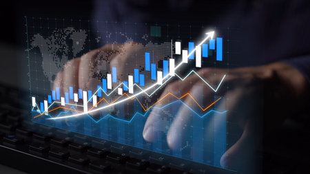 A business professional utilizes a keyboard while analyzing financial graphs and data, showcasing an upward trend in the stock market. Insights and strategy are paramount.の写真素材