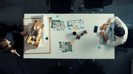 Top down aerial view of project manager using laptop to analysis building construction. Aerial view of engineer planning and writing at sticky note while brainstorming house structure.の写真素材
