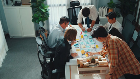 Group of diverse team planning strategy while sitting at table with project plan. Top aerial view of...
