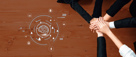 This image features multiple hands coming together on a wooden table, symbolizing teamwork and...