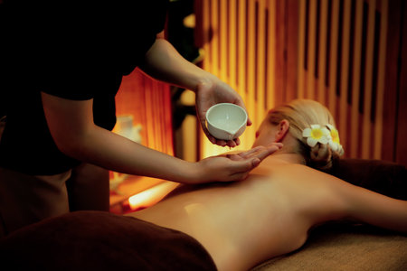 Masseur hands pouring aroma oil on woman back. Masseuse prepare oil massage procedure for customer at spa salon in luxury resort. Aroma oil body massage therapy concept. Quiescentの写真素材
