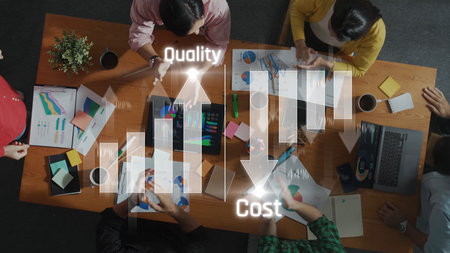 A top-down view of a collaborative business meeting featuring charts and graphs focused on quality...