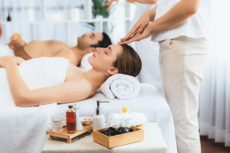 Caucasian couple enjoying relaxing anti-stress head massage and pampering facial beauty skin recreation leisure in dayspa modern light ambient at luxury resort or hotel spa salon. Quiescentの写真素材